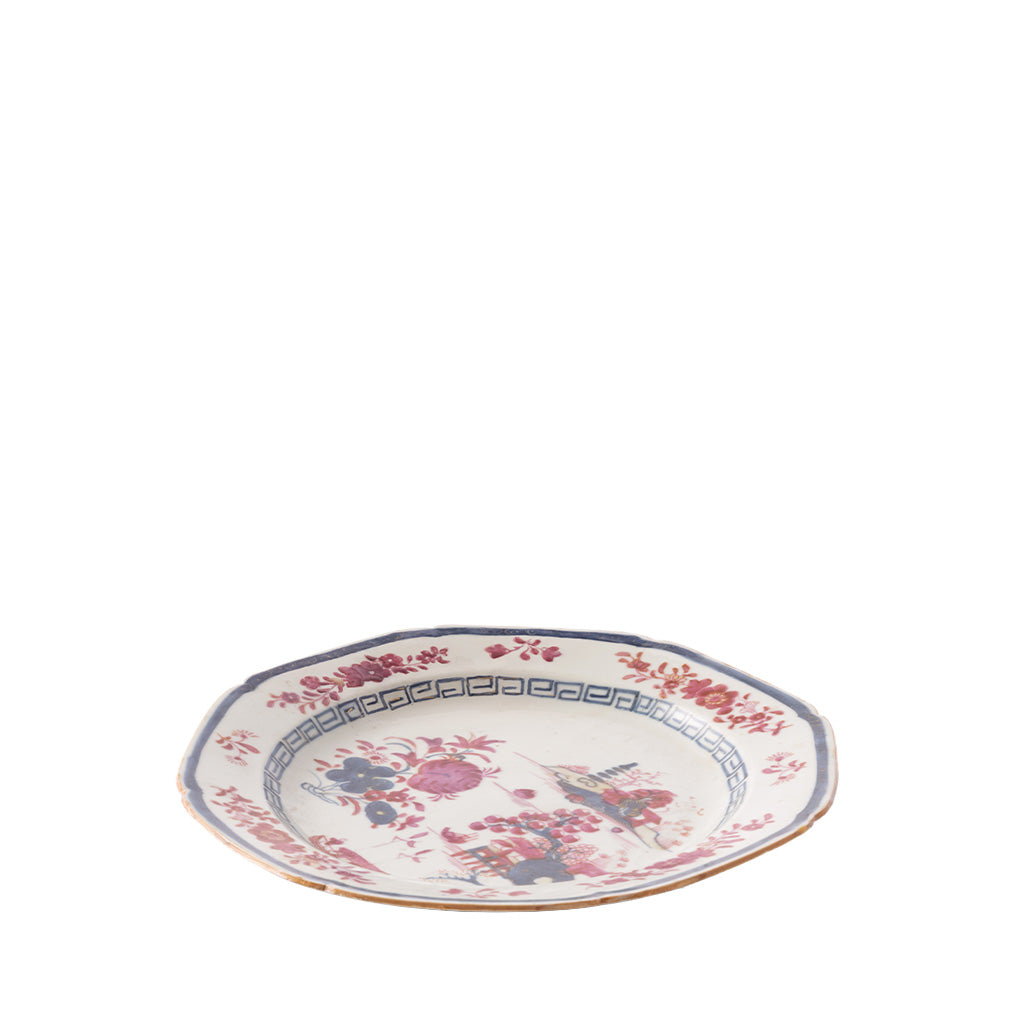 A shallow ceramic bowl with a scalloped rim features delicate pink and blue floral designs, a blue geometric border, and a thin gold-trimmed edge. The center is decorated with floral arrangements and an illustrated scene with birds and garden elements, giving the piece a vintage-inspired look.