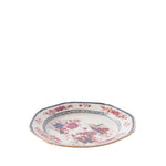 A shallow ceramic bowl with a scalloped rim features delicate pink and blue floral designs, a blue geometric border, and a thin gold-trimmed edge. The center is decorated with floral arrangements and an illustrated scene with birds and garden elements, giving the piece a vintage-inspired look.