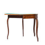 A side view of a wooden drop-leaf table with one leaf extended reveals a green felt-lined playing surface and hinged construction. The table features a warm wood finish, subtle veneer detailing, and gracefully curved legs in a classic antique style.