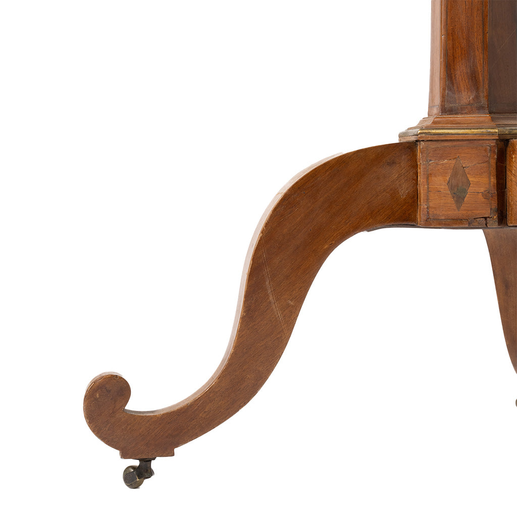 Close-up of the lower right corner of a polished wooden table, showing a curved apron, drawer front, and small caster wheel on a white background.