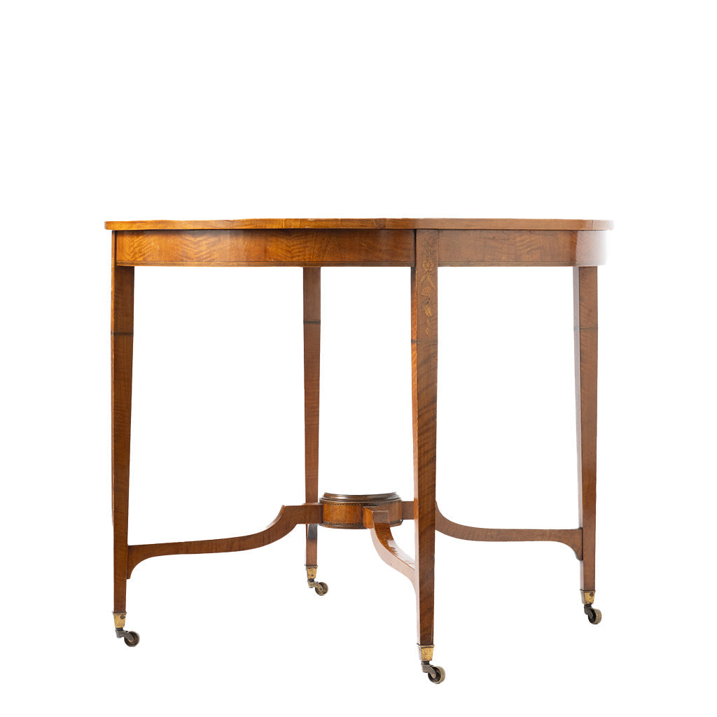 A round wooden table with legs on casters, featuring a warm medium-brown wood finish and brass hardware.