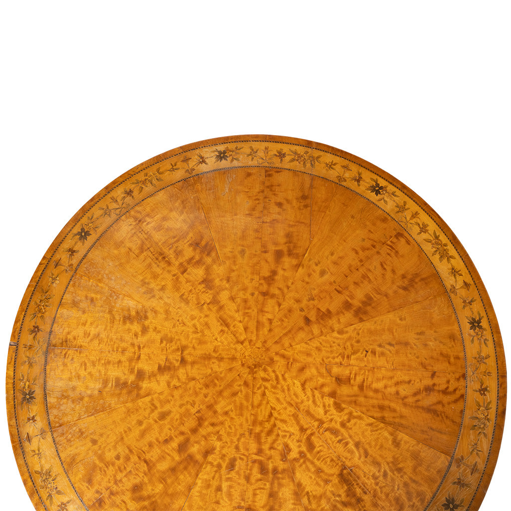 A close-up top-down view of a round wooden table top with a richly figured burl wood grain and an inlaid star pattern around the edge, set against a plain white background.
