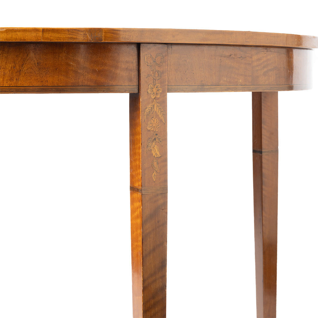 Close-up of a polished wooden table leg with decorative inlay, showing warm brown wood grain and a white background.
