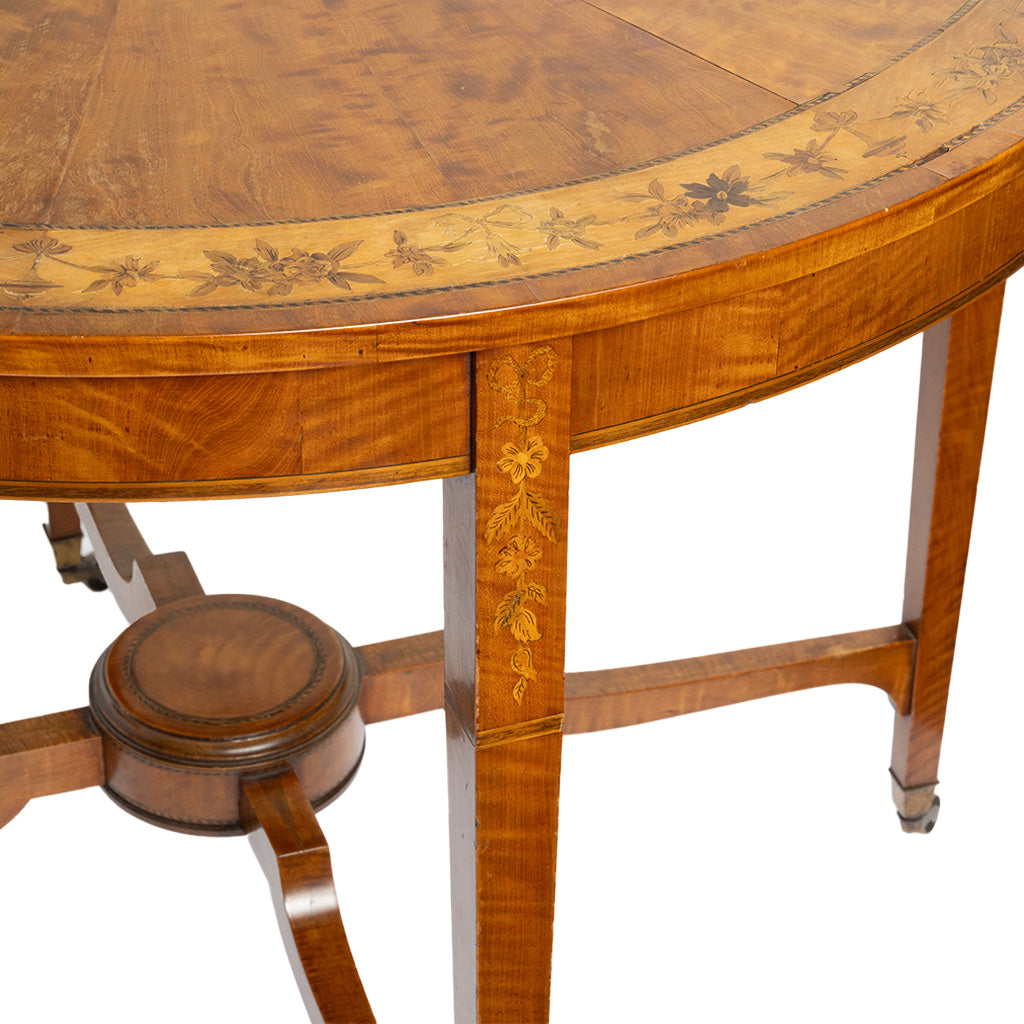 Close-up of a polished wooden table showing the curved tabletop with floral inlay, a decorative apron panel, and legs on a white background.