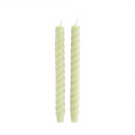 Two twisted green candles on a white background