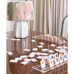 Tabletop game with numbered tiles on a wooden table, lamp in the background