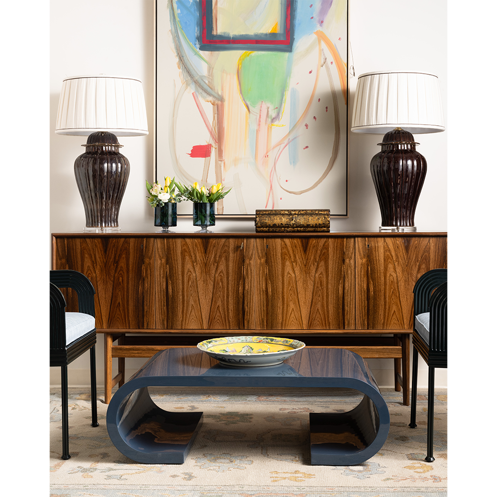 Modern living room with a coffee table, lamps, and abstract art on the wall.