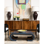 Modern living room with a coffee table, lamps, and abstract art on the wall.