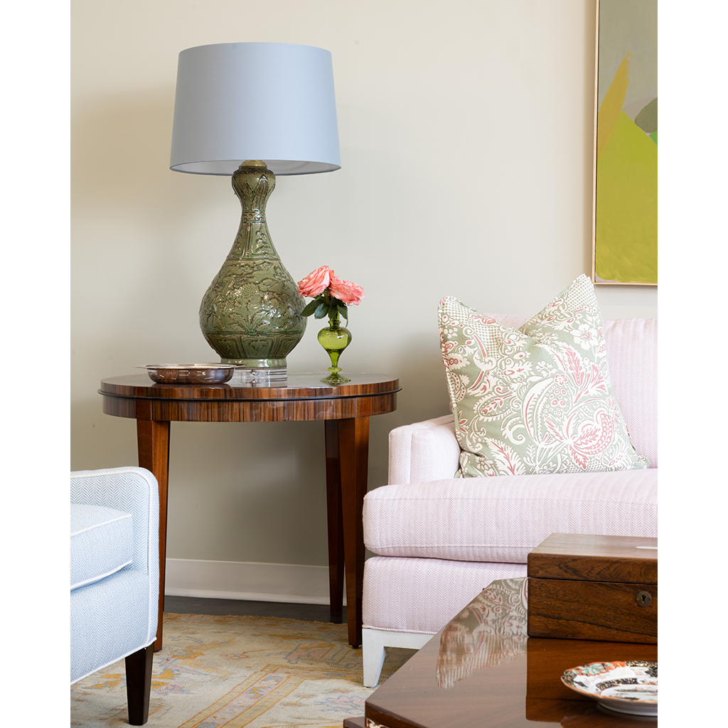 Living room with a side table, lamp, and sofa with decorative pillows.