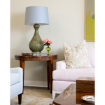 Living room with a side table, lamp, and sofa with decorative pillows.