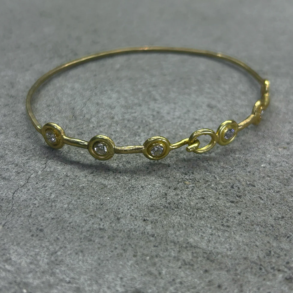 Gold bracelet with small diamonds on a gray surface