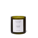 A scented candle in an olive green glass jar with a white label reading 'FLAMINGO ESTATE HEIRLOOM TOMATO' on a clean white background.