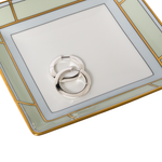 Silver ring holder on a decorative glass plate with gold frame