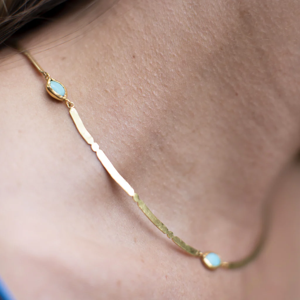Gold necklace with opal stones on a person's neck