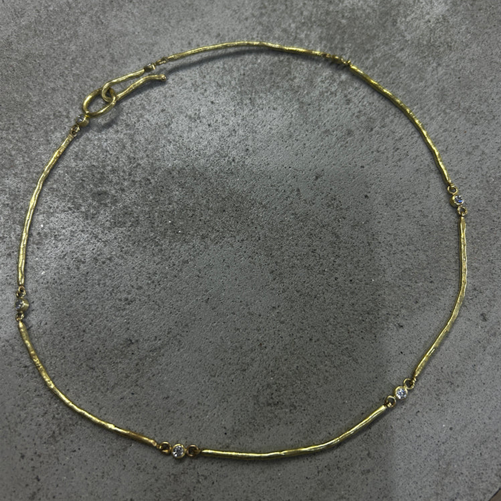 Gold necklace with small diamonds on a gray surface