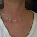 Close-up of a person wearing a gold necklace with Diamond stations wearing a white shirt.