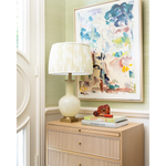 Decorative interior scene with a lamp, books, and artwork on a cabinet.