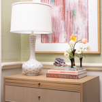 Decorative setup with a lamp, books, and flowers on a wooden surface.