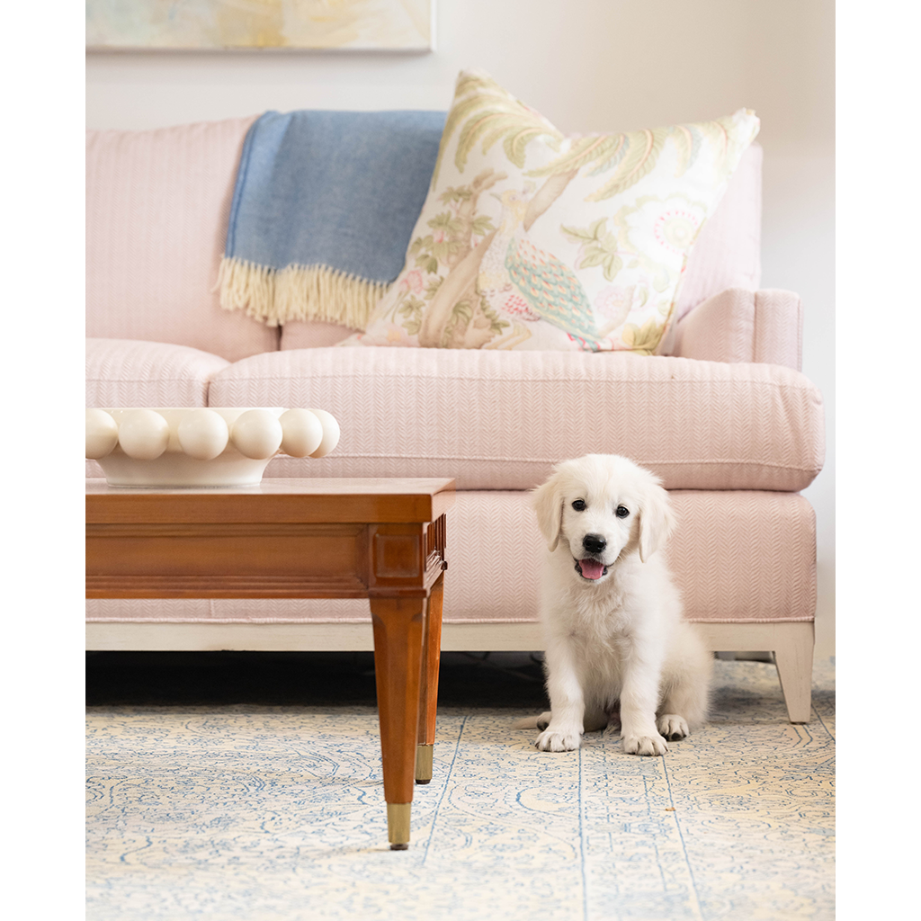 White decorative Halo Bowl with rounded bead design on wooden coffee table in front of pink sofa and pillows.
