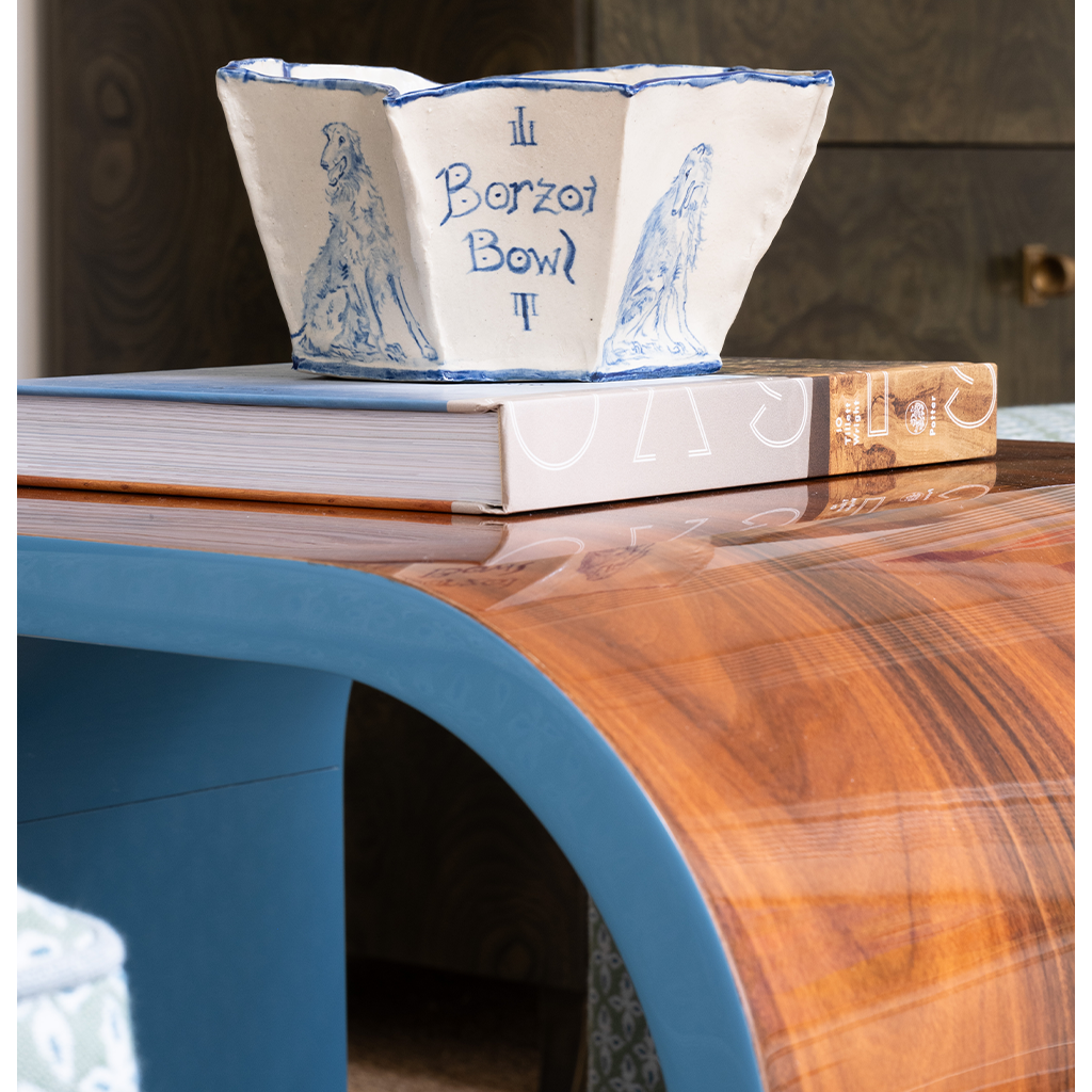 Decorative blue and white bowl on top of books with a wooden surface and blurred background