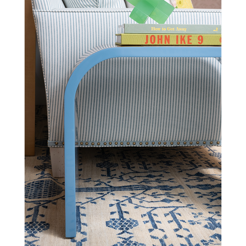Blue side table next to a striped cushion sofa and books on a patterned rug