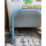 Blue side table next to a striped cushion sofa and books on a patterned rug