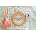 Salmon-colored Lexington dinner plate layered with a butterfly-printed salad plate on a green and white floral placemat with .