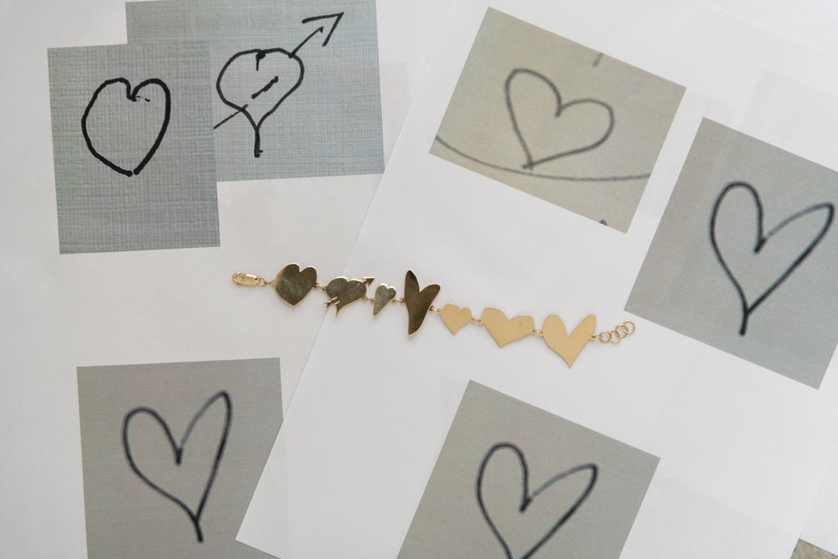 An All My Hearts bracelet laid flat across some drawn hearts