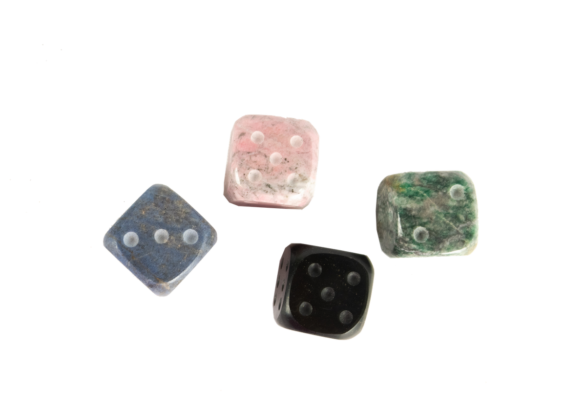 An aerial view of andean stone dice, set of four. Each dice is a different color: pink, blue, green, black