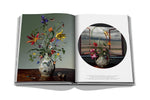 Open art book featuring detailed floral paintings with vibrant reds, yellows, and greens on glossy pages.