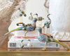 cloisonne birds stacked on books