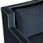 Close-up of a dark blue upholstered headboard with a pillow on a white background