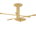 A modern pendant with a brushed gold finish, featuring a central column, four flat geometric blades, and a dome-shaped light fixture, shown against a solid white background.