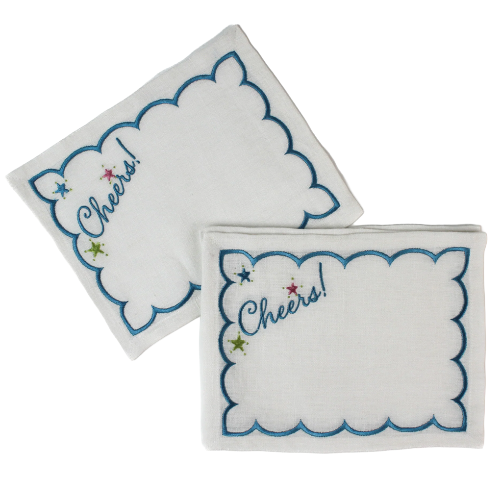 Two white embroidered napkins with scalloped edges, blue borders, and 'Cheers!' script with small star accents, shown on a white background.