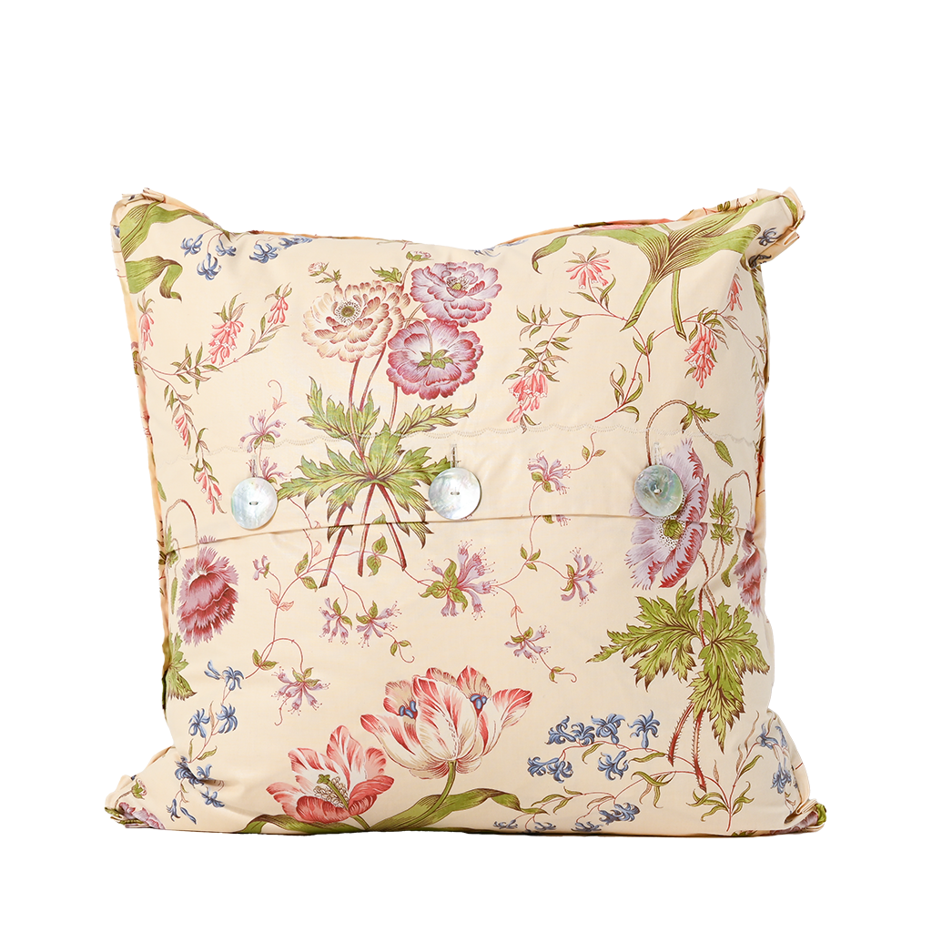 Floral patterned pillow with decorative buttons on a white background