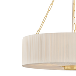 Close-up of a modern drum pendant light with a pleated off-white fabric shade and polished gold metal chain suspension against a white background.