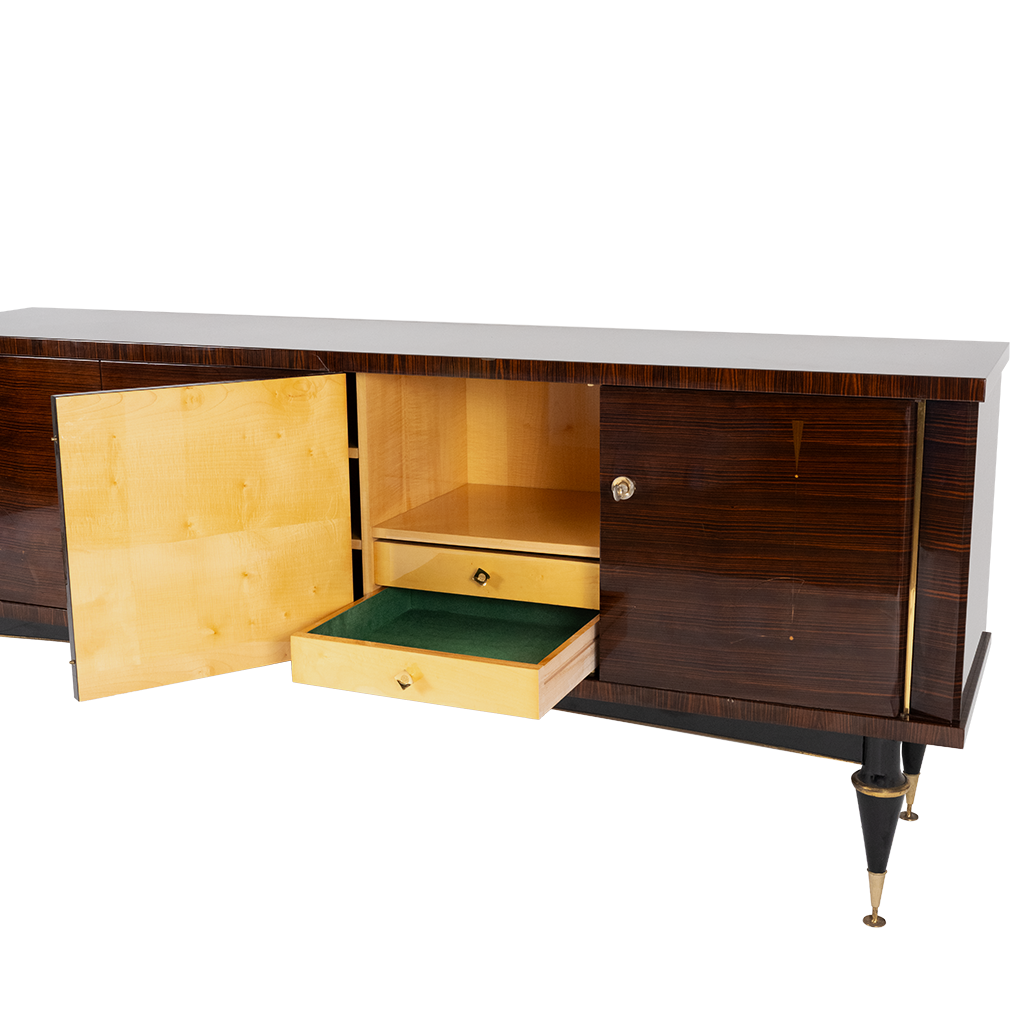 French mid-century modern lacquered sideboard, in the manner of Jacques Adnet. Rectangular case fitted with two sets of dual cabinet doors, one side opening to two drawers, and storage compartment, mirrored bottom panel, interior lighting in need of wiring, opposite side opening to two shelves, case rising on tapered legs ending on brass feet.