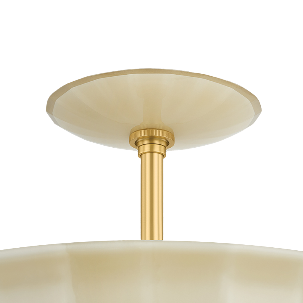 Close-up of a ceiling light fixture showing a brushed gold metal stem and canopy with a cream-colored glass shade against a white background.