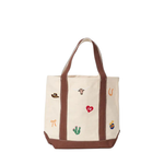 An off-white canvas tote bag with brown leather handles and base, decorated with small embroidered western-themed motifs including a cowboy hat, longhorn, horseshoe, cactus, and red heart.