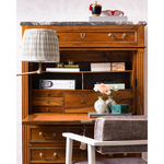 A styled home decor scene featuring two marbled ceramic vases with flowers, set against a wooden dresser background with books.