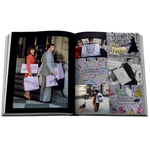An open hardcover book spread showing multiple fashion and shopping-themed photographs, including people carrying Louis Vuitton and Burberry Goodman bags, on a plain white background.