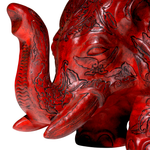 Red elephant statue with intricate carvings on a white background