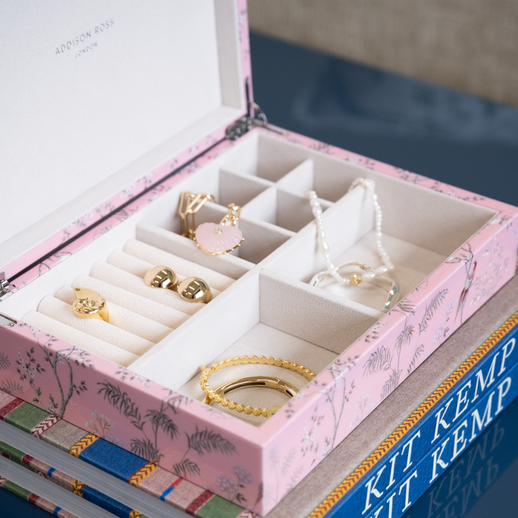 Pink jewelry box with compartments containing jewelry