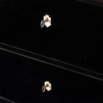 A close-up of an antique ebonized chest of drawers highlights the glossy black finish and ivory-colored shield-shaped keyhole escutcheons, each fitted with its original key. The image emphasizes the chest's clean lines and understated craftsmanship.
