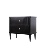 A three-quarter view of an antique ebonized two-drawer chest features a sleek black finish, clean lines, and tapered legs. Small ivory-colored keyhole escutcheons provide a subtle contrast, emphasizing the chest's refined, minimalist design.