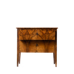 A vintage wooden nightstand with two drawers featuring intricate marquise-shaped wood grain patterns, small dark metal pulls, and tapered legs, shown against a plain white background.
