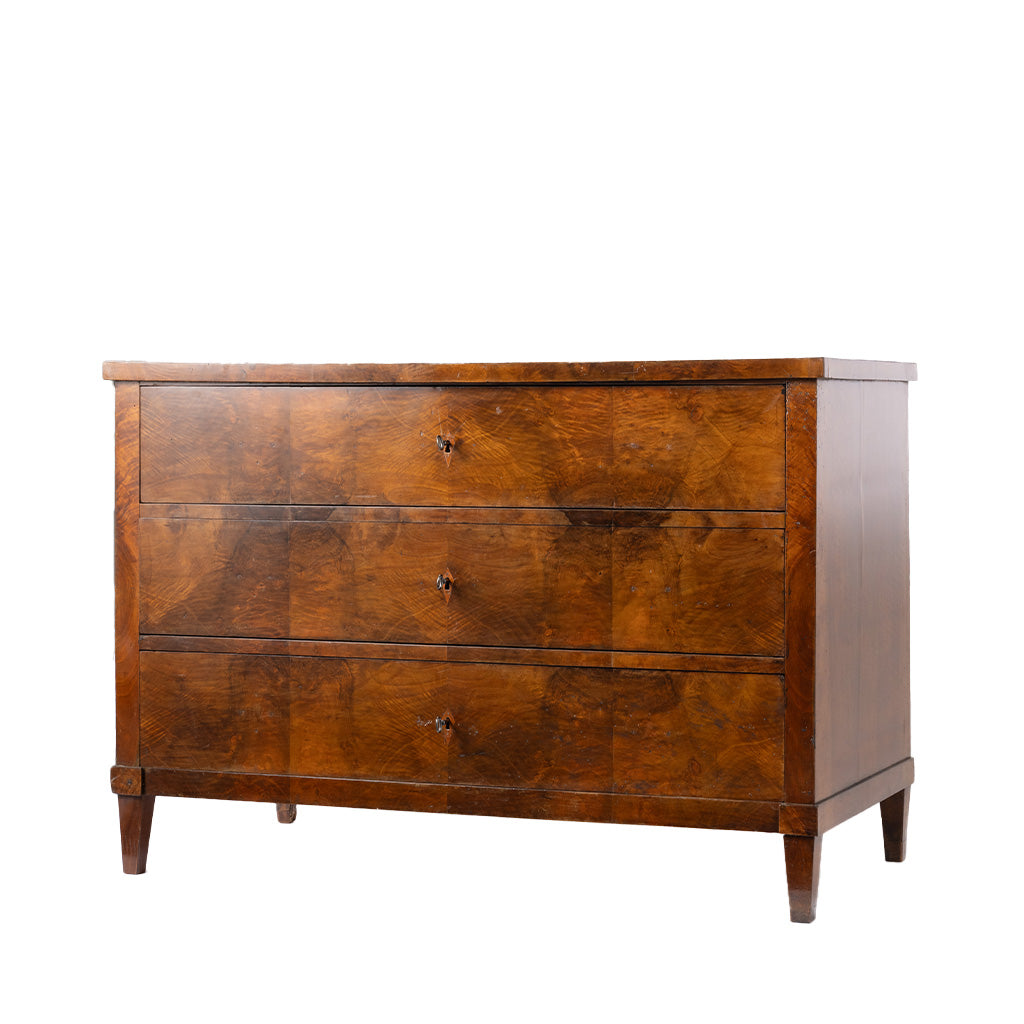 A three-drawer wooden chest of drawers with a rich warm brown grain pattern and small round metal knobs, shown against a plain white background.