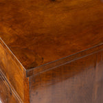 Close-up of a polished dark brown wooden furniture piece, showing the rich wood grain and corner joint detail.