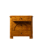 A front view of an antique Biedermeier chest of drawers shows the top drawer partially open, revealing dovetail joinery and a solid wood interior. The richly figured golden burl wood veneer, arched veneer detailing across the lower drawers, and block feet highlight the piece's exceptional craftsmanship and elegant design.
