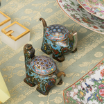 Decorative turtle-shaped cloisonne figurines on a patterned tablecloth